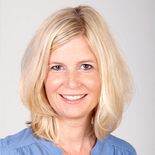 Portrait einer Frau mit blondem, halblangem Haar und hellem Oberteil.